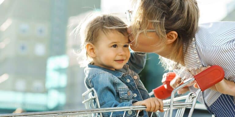 A letter to the mom dealing with a public tantrum mom kissing toddler sitting in a shopping cart- public tantrum