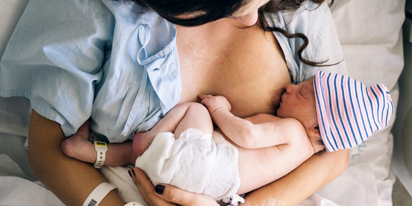 Scared of breastfeeding? An expert shares tips on overcoming common breastfeeding fears woman breastfeeding newborn baby in hospital - overcoming breastfeeding fears