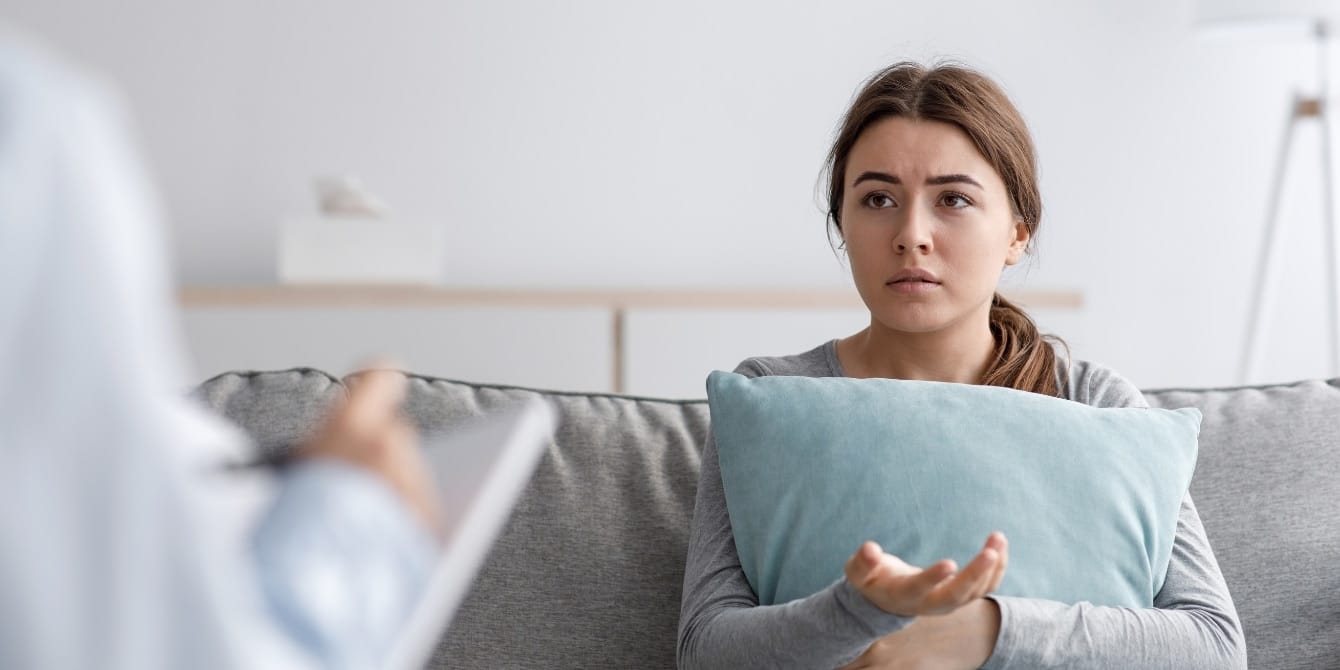 70% of women have experienced gaslighting in their fertility journey, survey shows Young woman at Doctor's visit confused- medical gaslighting in fertility