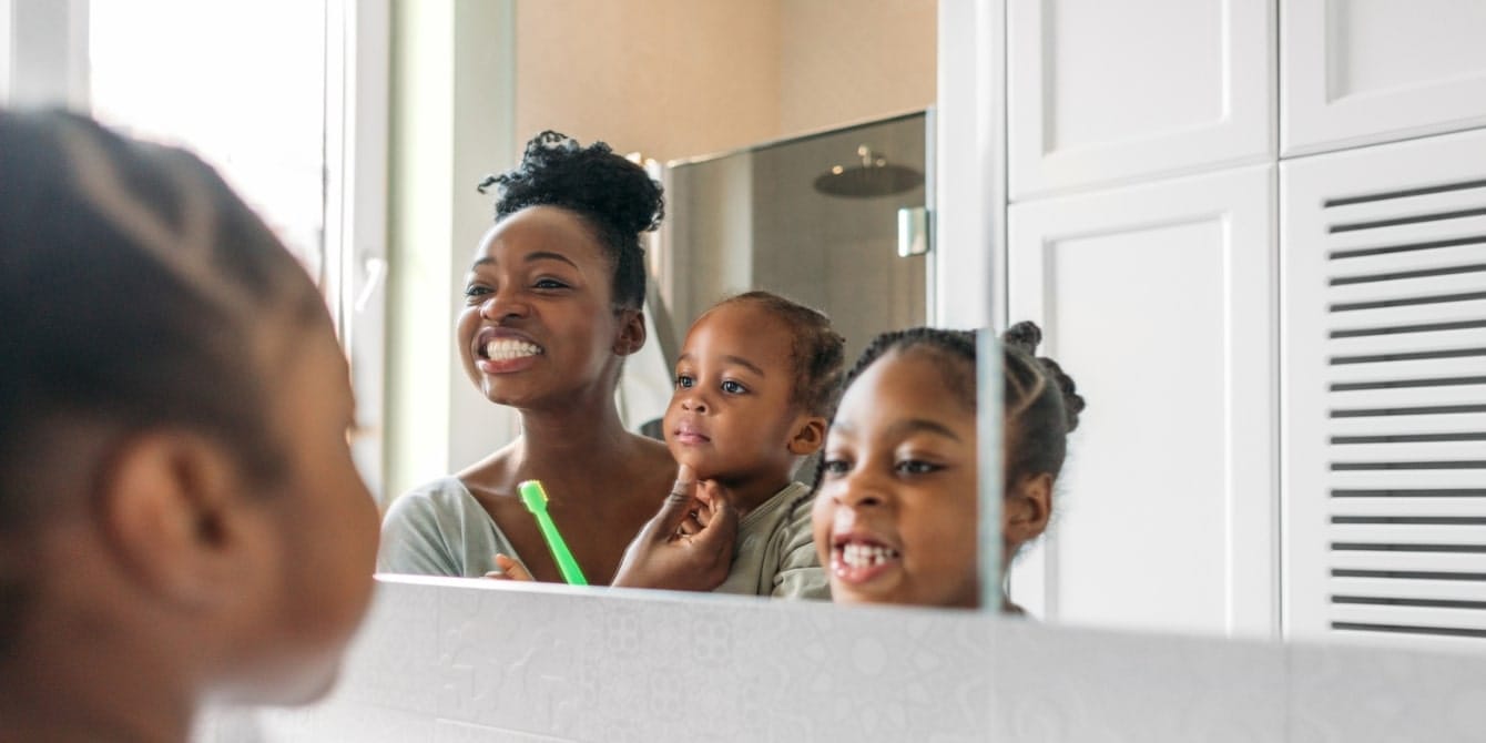7 ways to incorporate sustainable practices into your child’s daily routine reflection of mom and two children brushing their teeth in a mirror