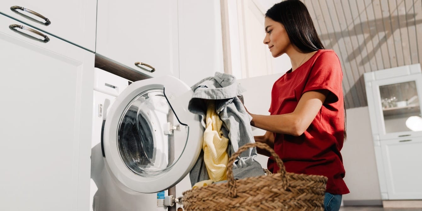 TikToker shares wild and effective alternative to fabric softener Woman loading laundry into washing machine.