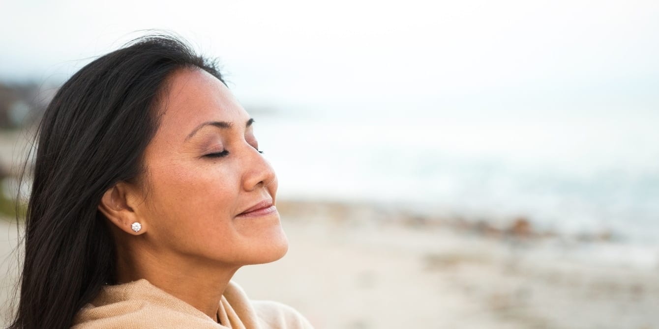 Should you try an at-home menopause test? confident woman at beach with eyes closed - at-home menopause testing