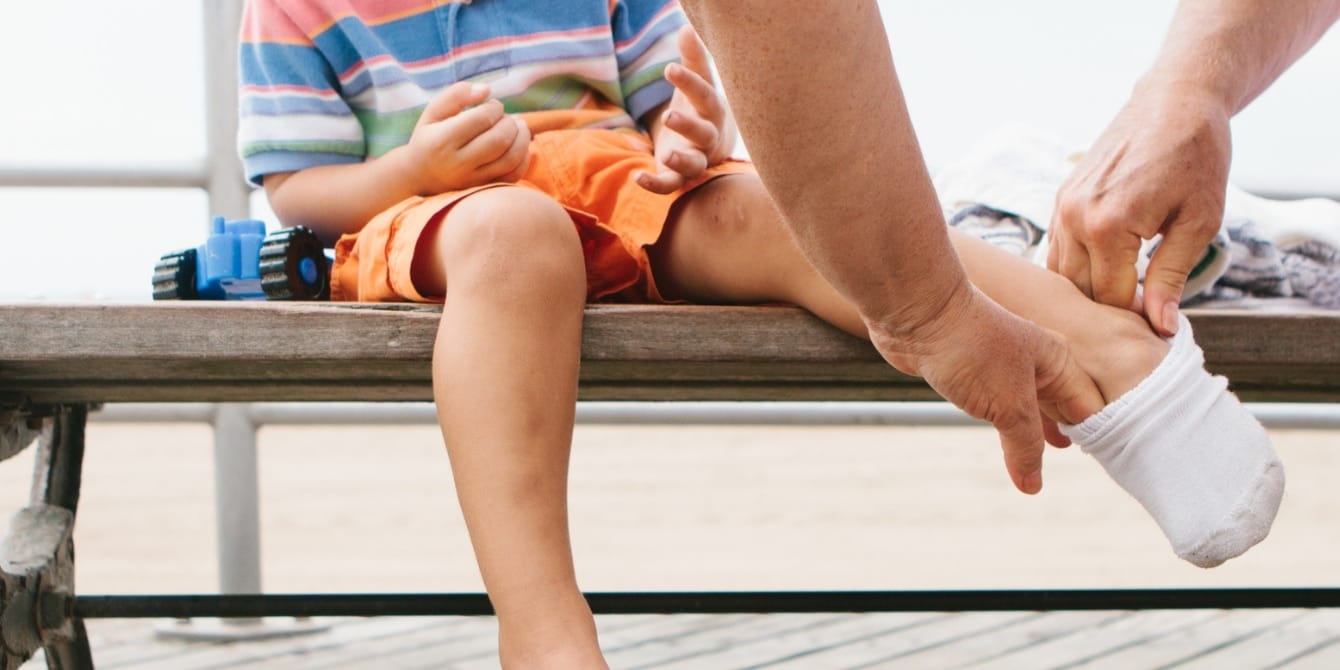 Mom shares tip for what to do with kids’ old or damaged clothes and mismatched socks parent's hands putting socks on child's feet