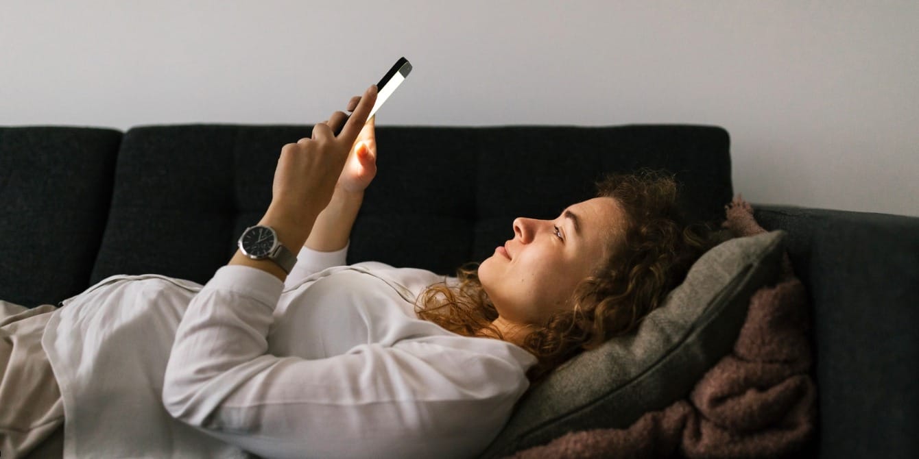 Dimming lights at night may lower risk of gestational diabetes, study shows pregnant woman looking at phone - evening light exposure and gestational diabetes risk