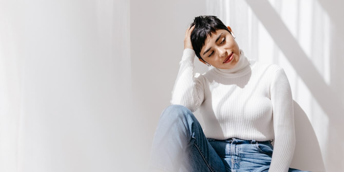 Millennials and Gen Z are feeling ‘parental milestone anxiety’, a psychologist shares latina woman sitting on the floor at home - parental milestone anxiety