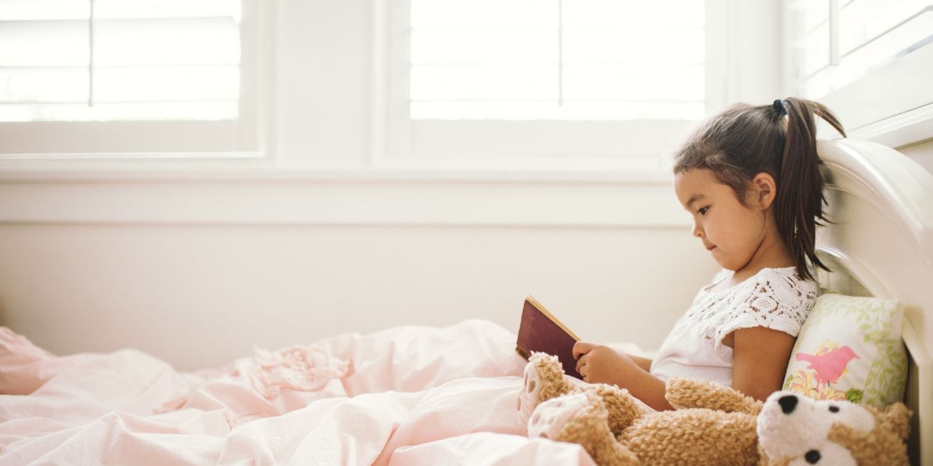Reading for pleasure has major benefits for kids, according to new research Little girl reading in bed