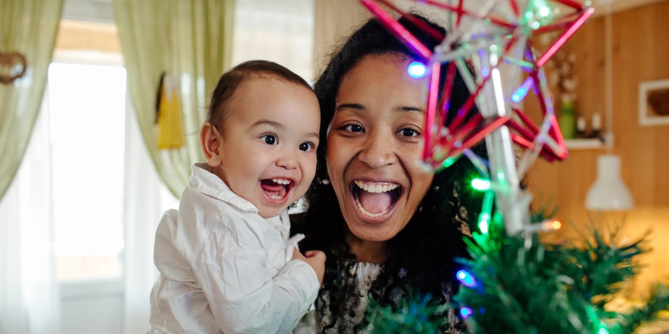 Making Christmas unforgettable: Beyond the lights and gifts mom and toddler smiling at Christmas tree star making Christmas unforgettable