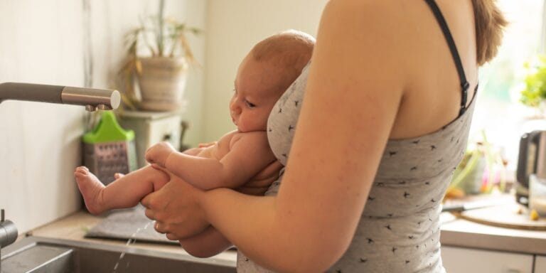 What is elimination communication? Experts share how to go diaper-free soon after birth mom holding baby practicing elimination communication
