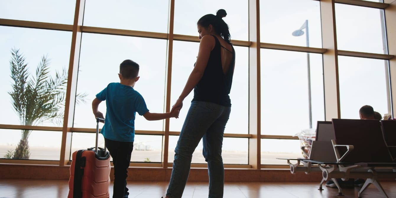 How to travel for the holidays when your child has autism or a disability, according to an occupational therapist mother and son at the airport traveling with a child with autism