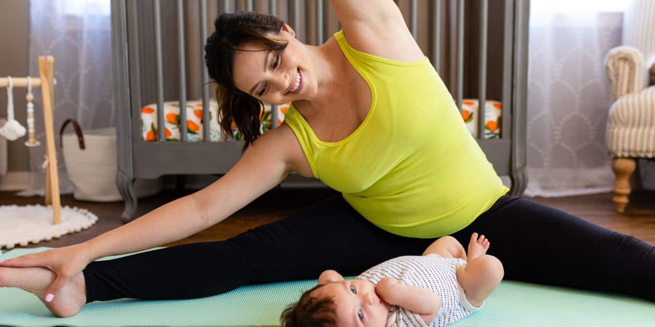 The 5 postpartum fitness apps we tell our best friends about mom stretching with baby on yoga mat - best postpartum fitness apps