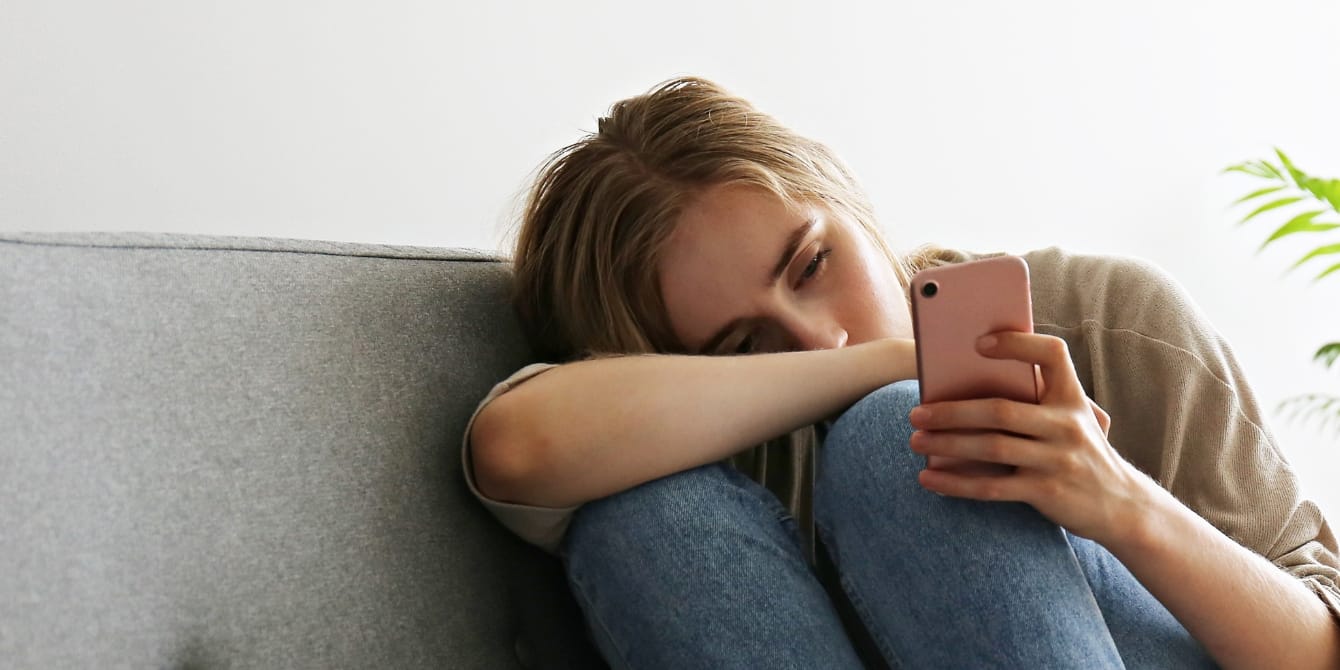 Female friendships after kids—where are my friends? sad woman scrolling on phone female friendships after kids