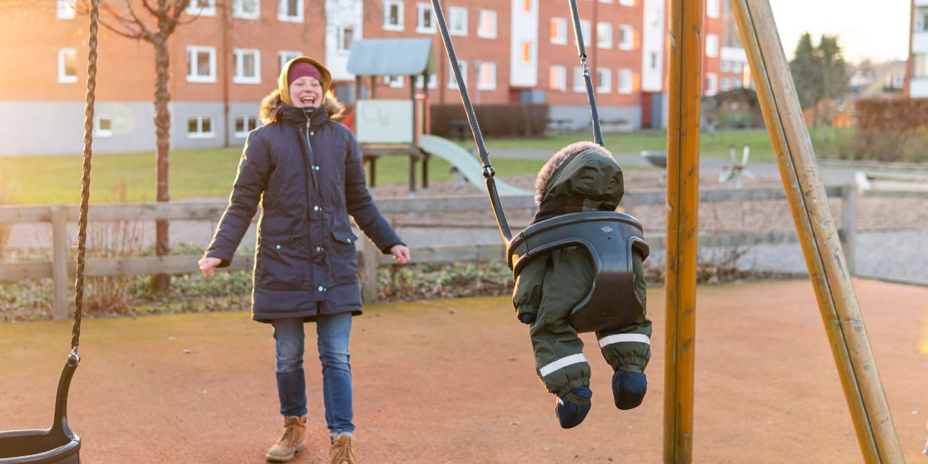 The happiest kids in the world have social safety nets happy mom pushing toddler on swings