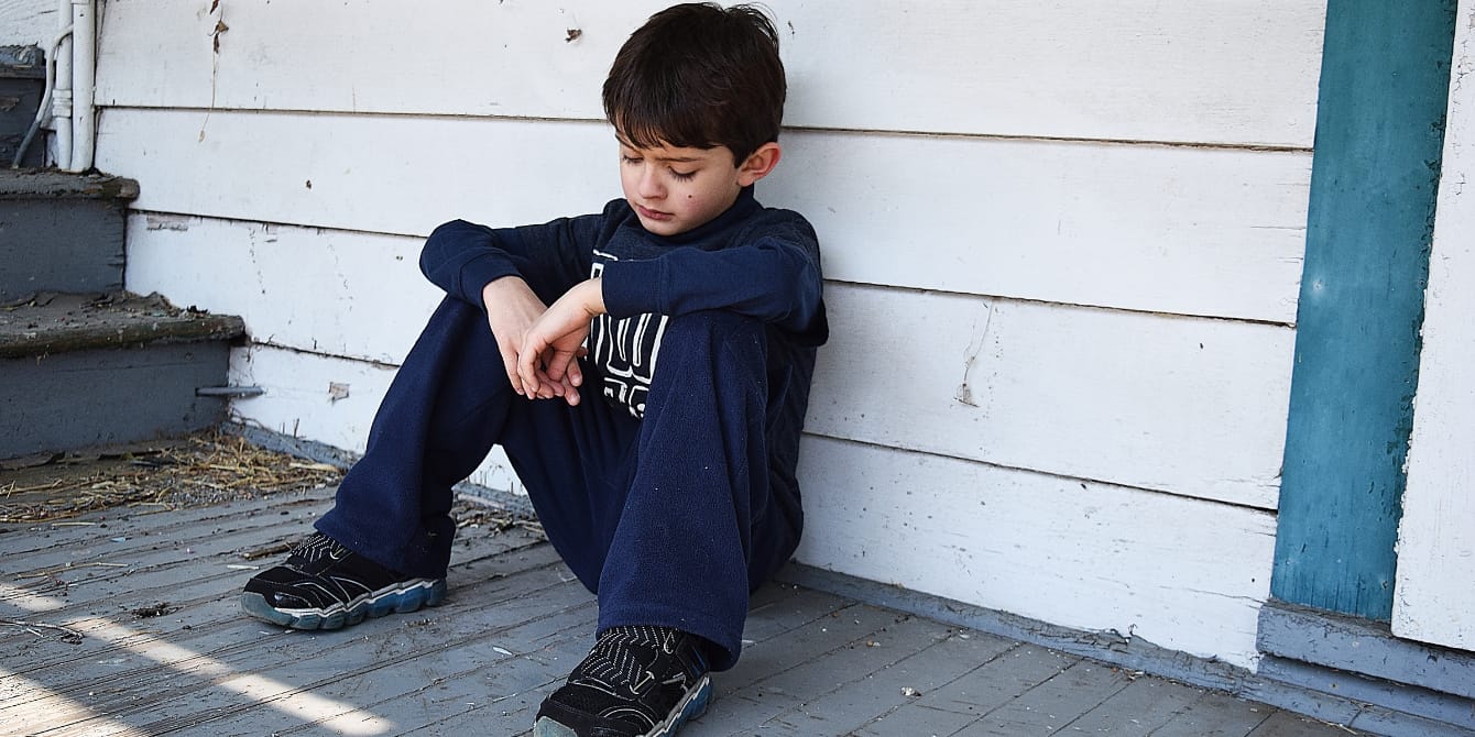 Breaking the generational cycle of poverty: Why safe and affordable homes are essential for children’s future sad child sitting in front of home affordable housing