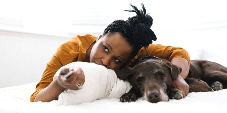 ‘Hurkle-durkle-ing’ is the hilarious-sounding TikTok trend you should absolutely be doing Woman lying in bed with dog watching tv