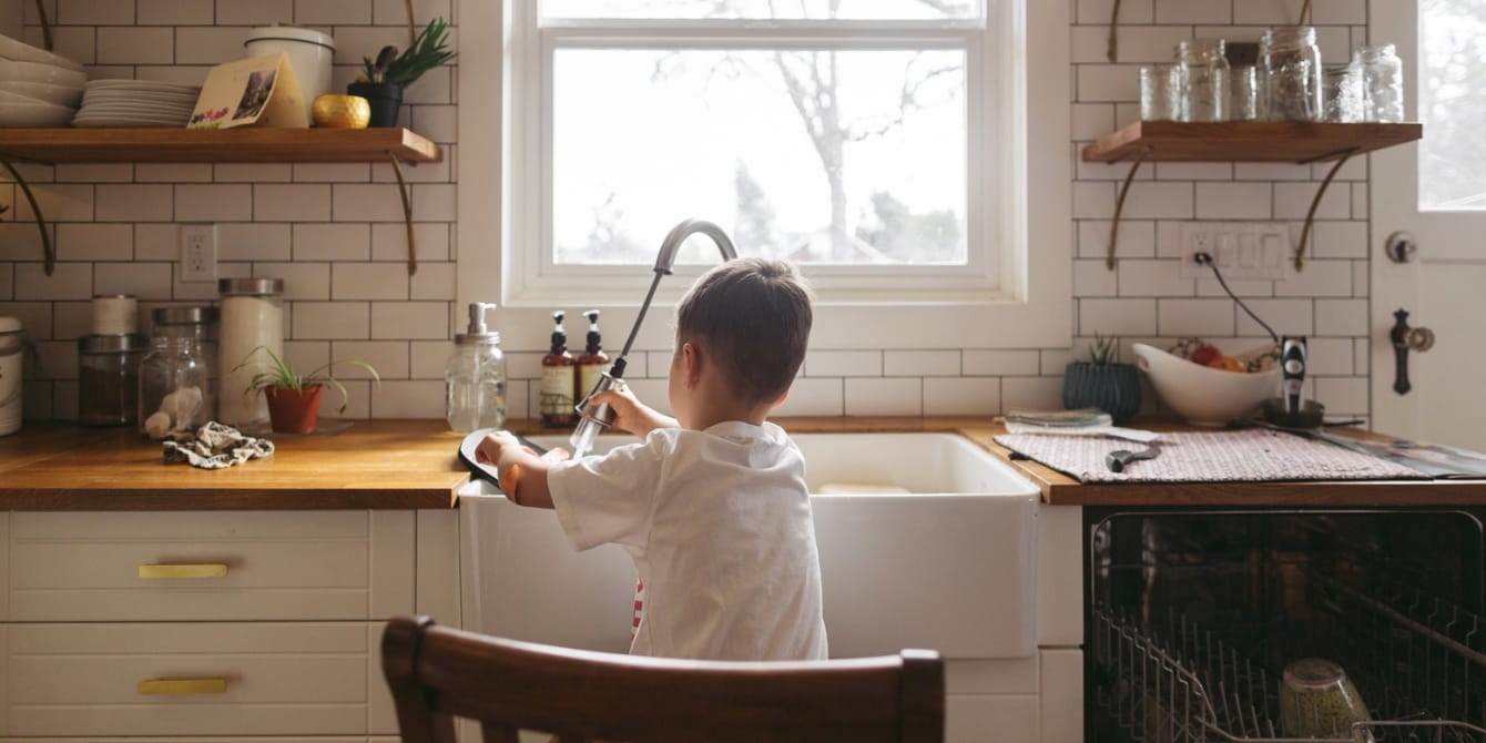 Psychologist reveals viral hack to teach kids about the mental load young boy doing dishes in the kitchen teaching mental load