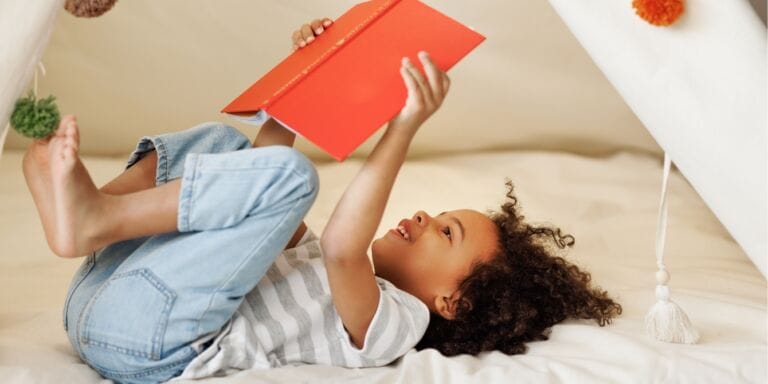 5 ways to raise little readers child reading a book in a fort - tips for raising readers