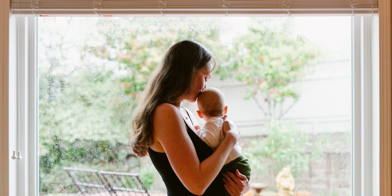Gen Z moms are less likely to support gun control and paid leave this election year, our survey shows mom kissing baby by window