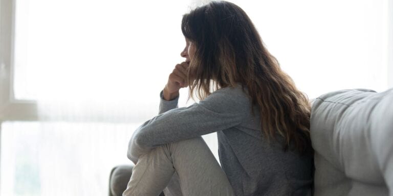 From postpartum depression to opioid addiction—and how I found my way back woman sitting on couch looking out window - opioid addiction