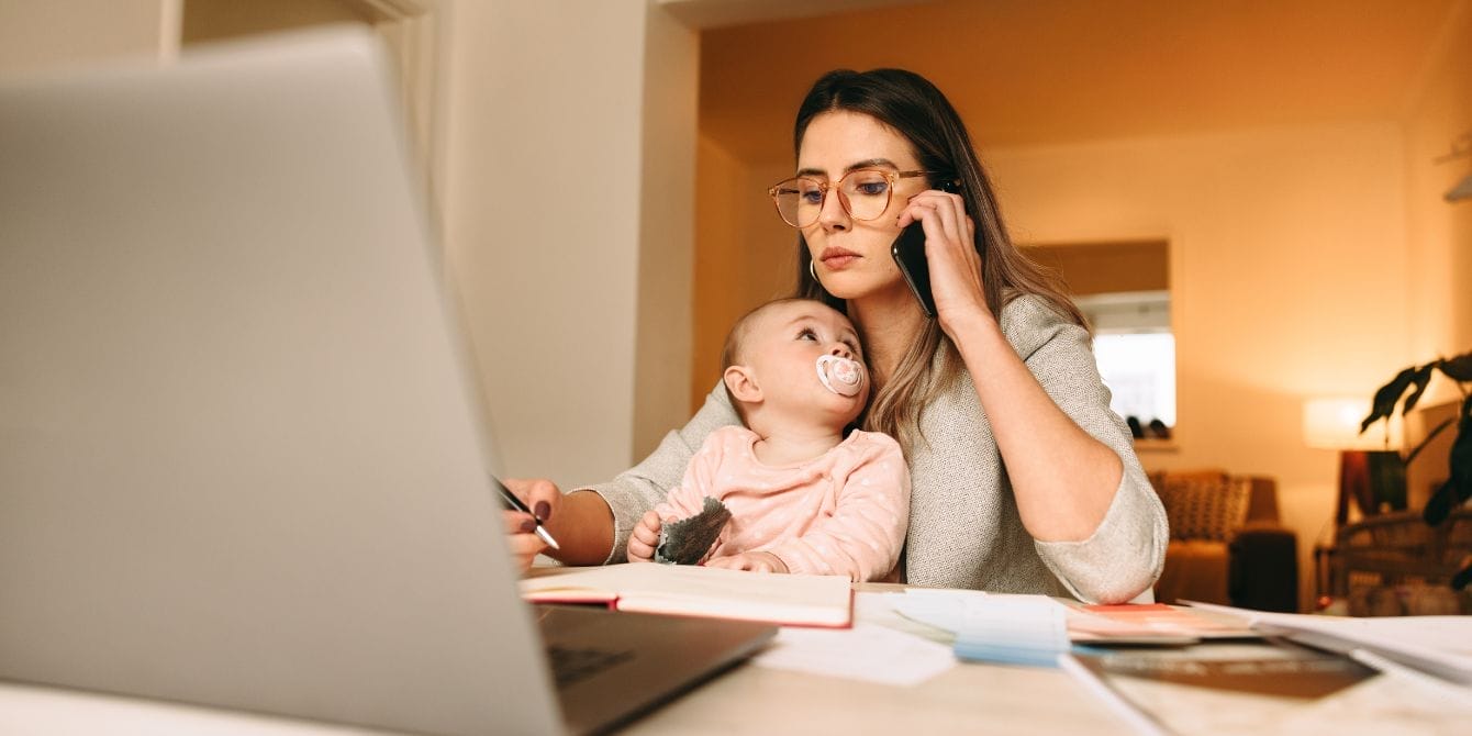 Work-life balance is impossible when you’re a work-from-home mom working from home with kids - mom on the phone working and holding baby