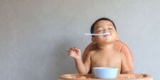 5 things to know about introducing solids, from a mom in the midst baby eating with spoon in mouth - introducing solids - motherhood essays - Motherly