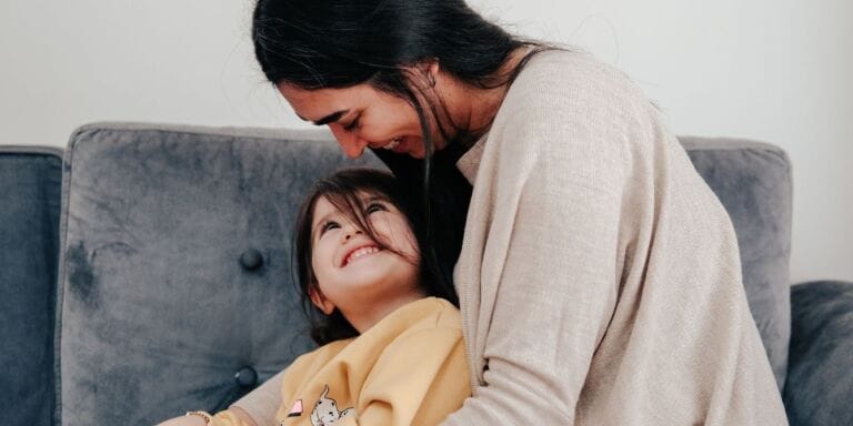 Does my toddler need speech therapy? mother hugging toddler on couch - does my toddler need speech therapy - motherly