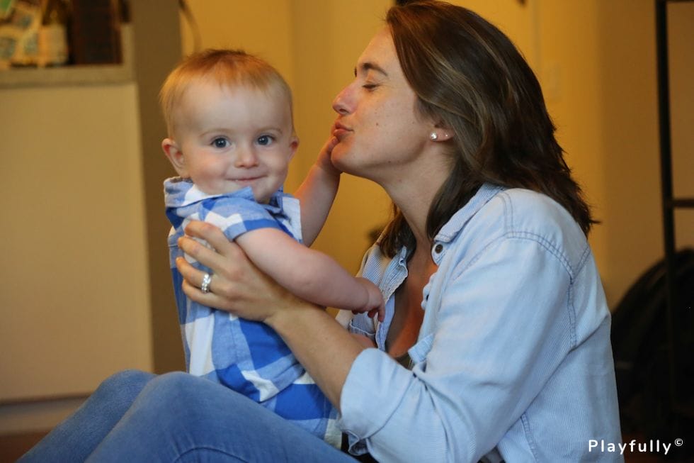 baby sitting in mom's lap, touching her face