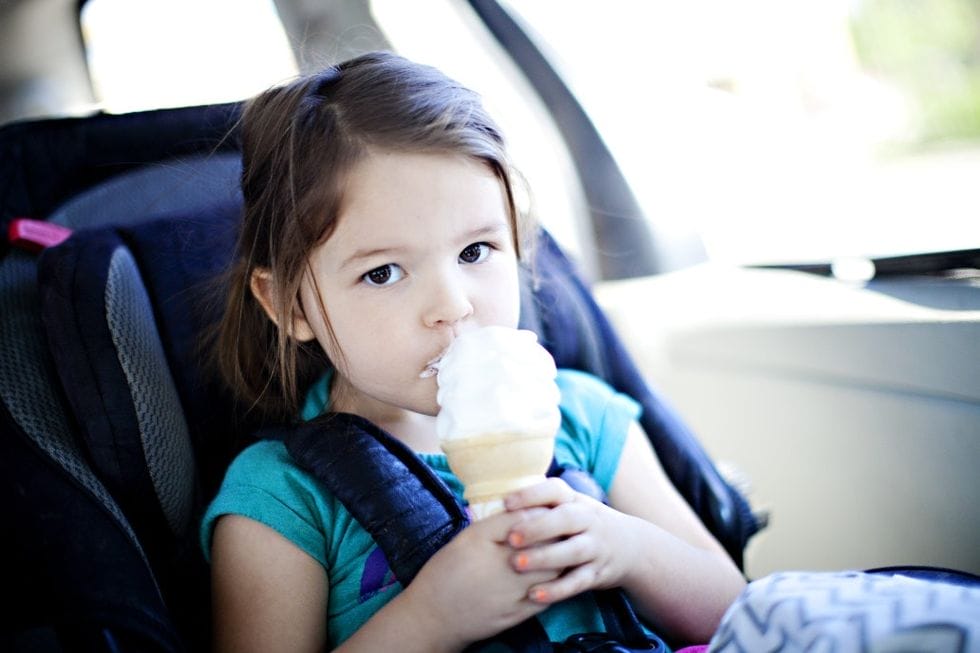 child eating ice cream cone in car seat booster - transition from car seat to booster